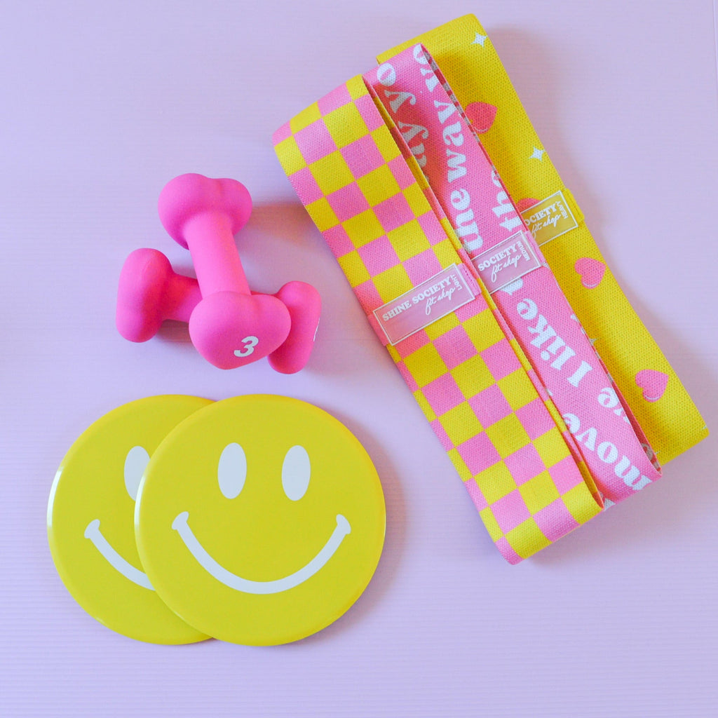 Three yellow hip resistance bands, 2 3 pound heart shaped dumbbells, 2 happy face sliding disks