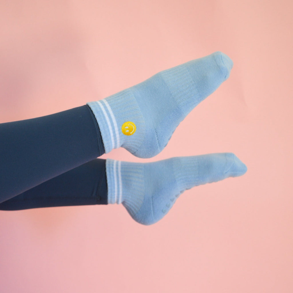 Light blue socks with a smiley face design on a pink background