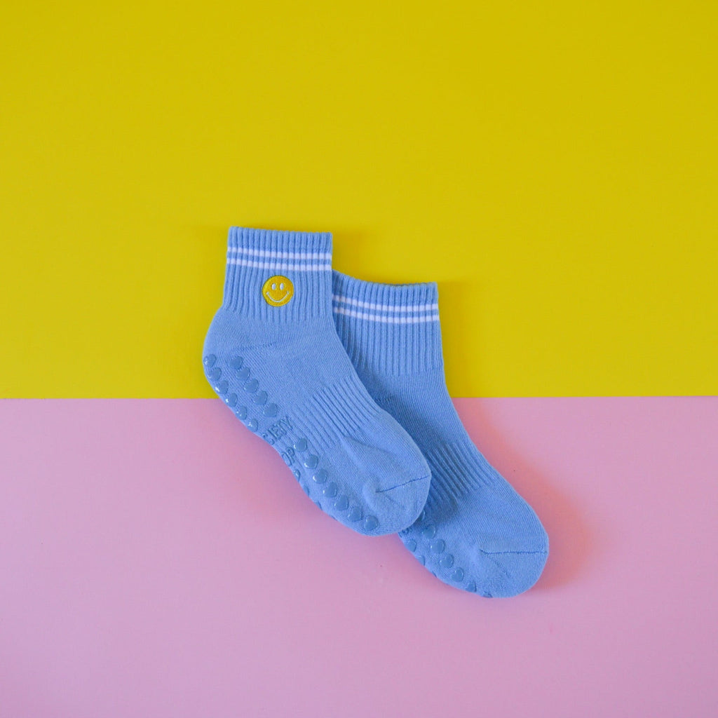 Blue socks with a smiley face on a yellow and pink background