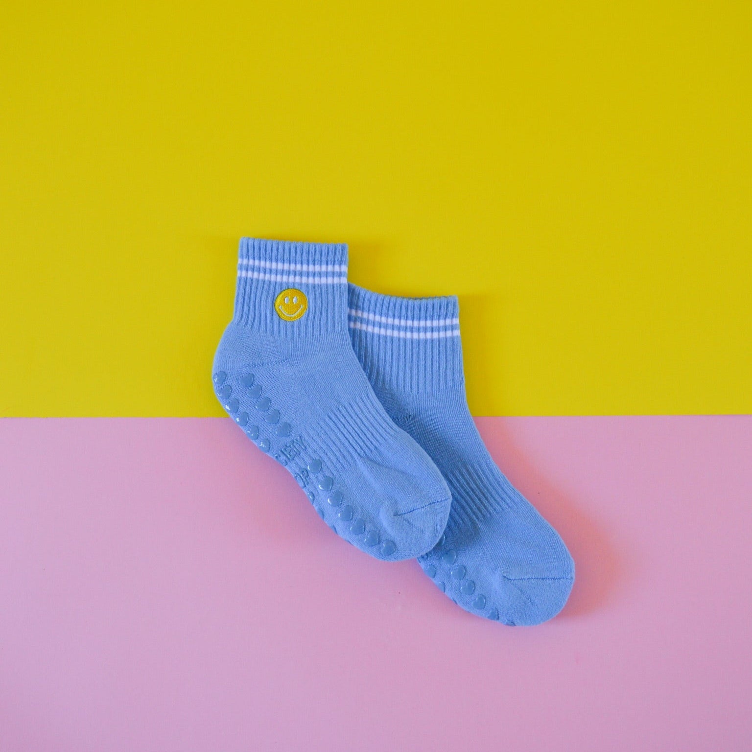 Blue socks with a smiley face on a yellow and pink background