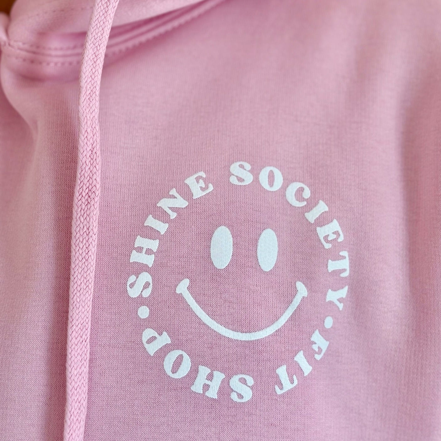 Pink hoodie with 'Shine Society Fit Shop' Happy face logo 