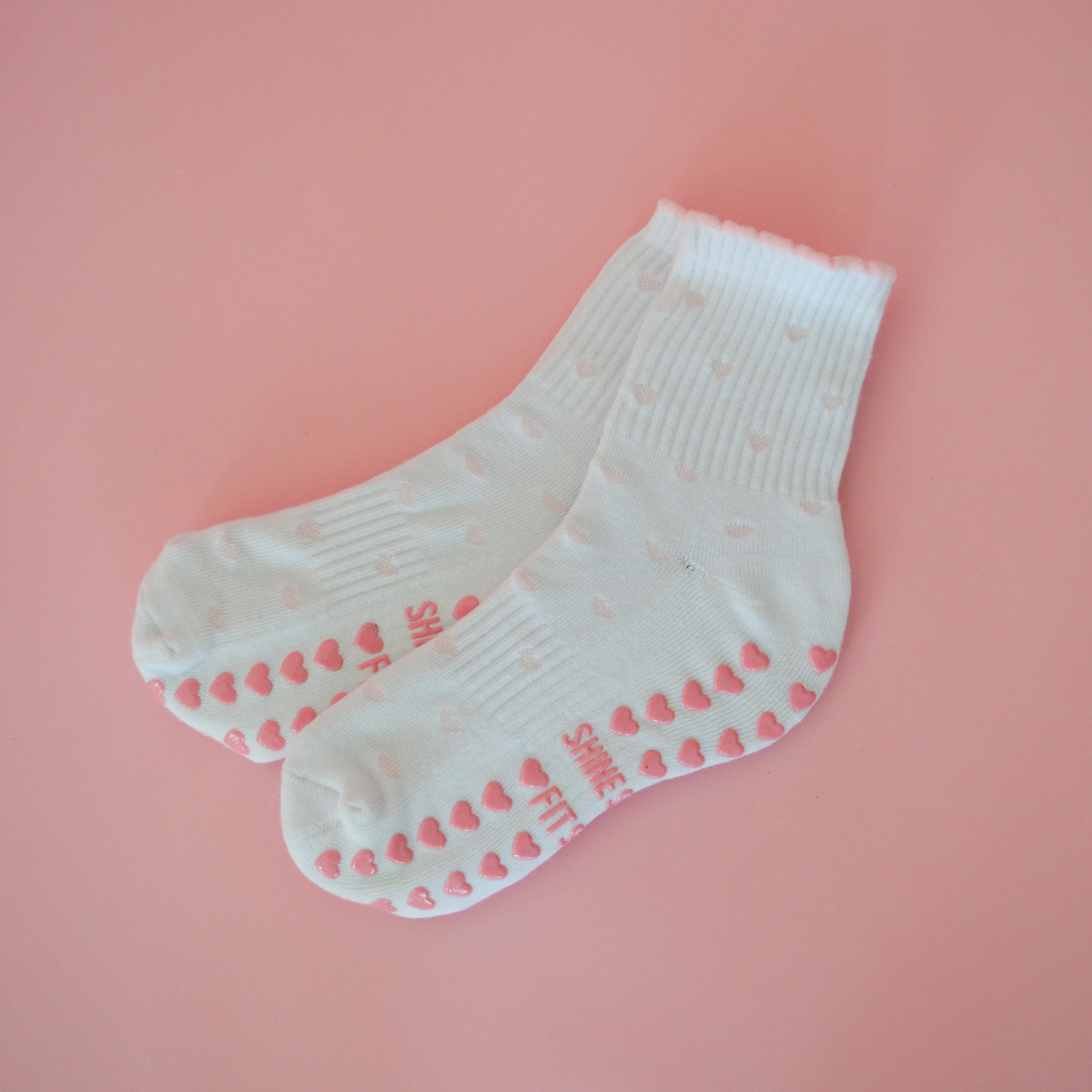 White socks with pink mini heart patterns on a pink background
