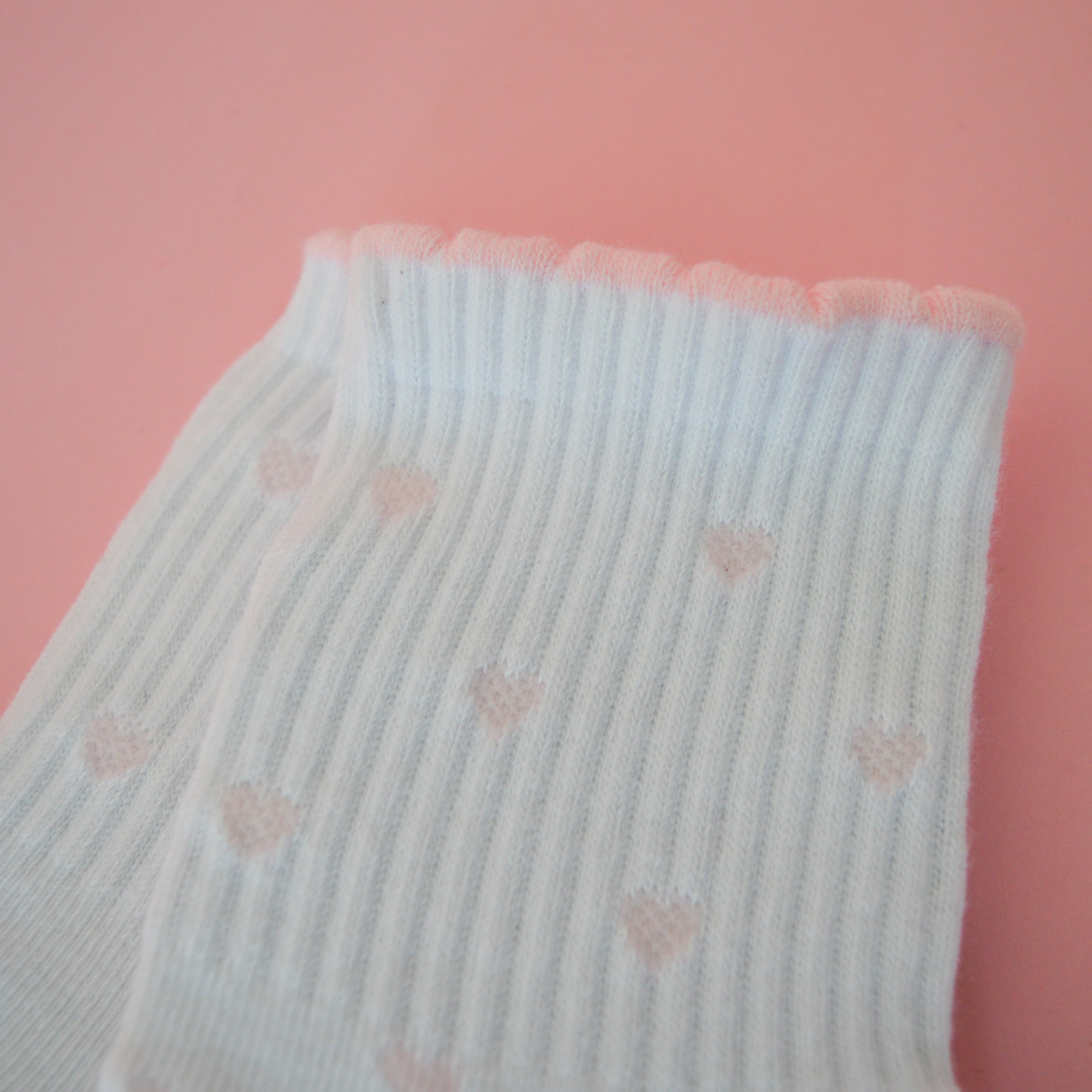 White sock with mini pink hearts on a pink background