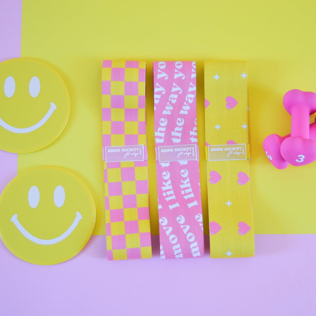 Three yellow hip resistance bands, 2 3 pound heart shaped dumbbells, 2 happy face sliding disks