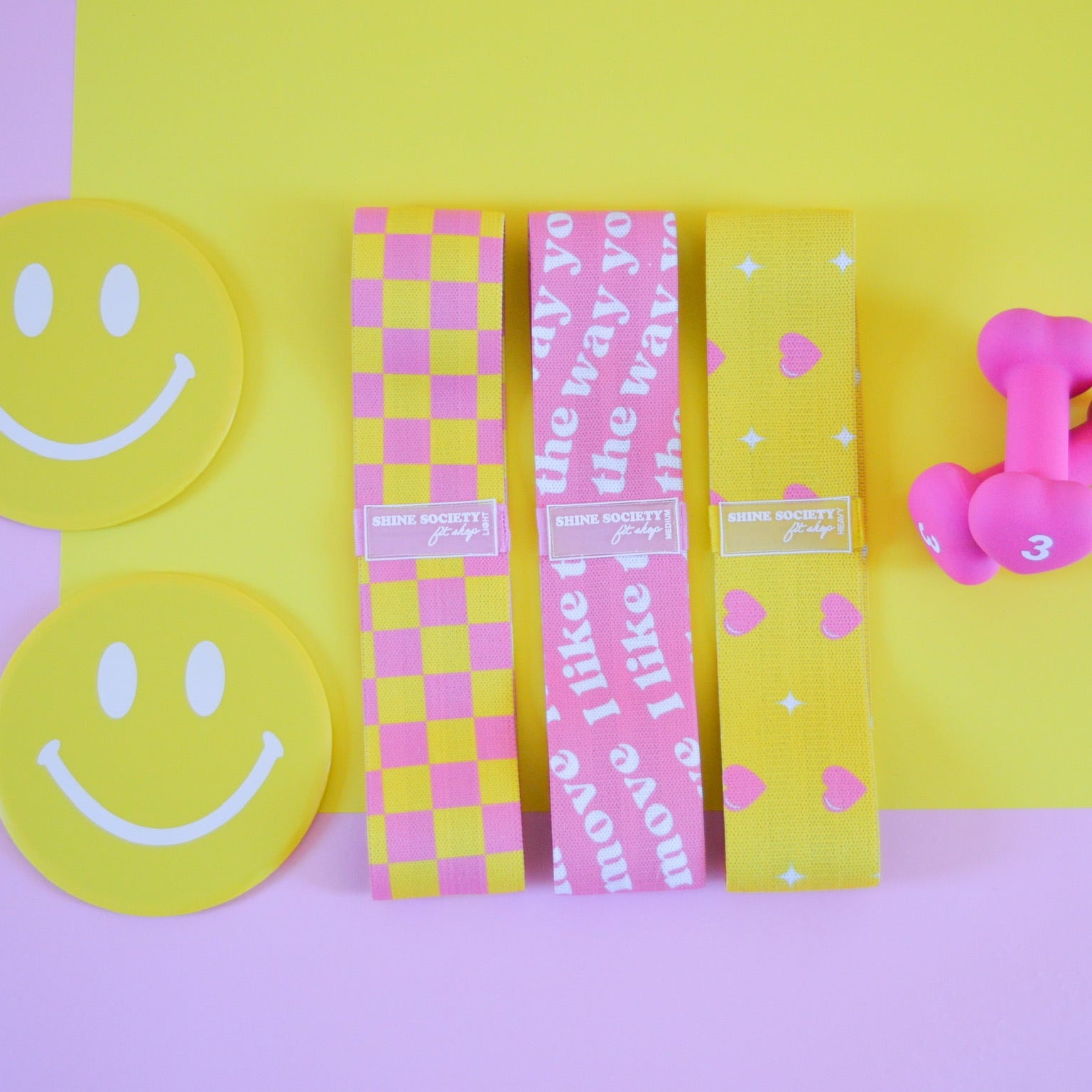 Three yellow hip resistance bands, 2 3 pound heart shaped dumbbells, 2 happy face sliding disks