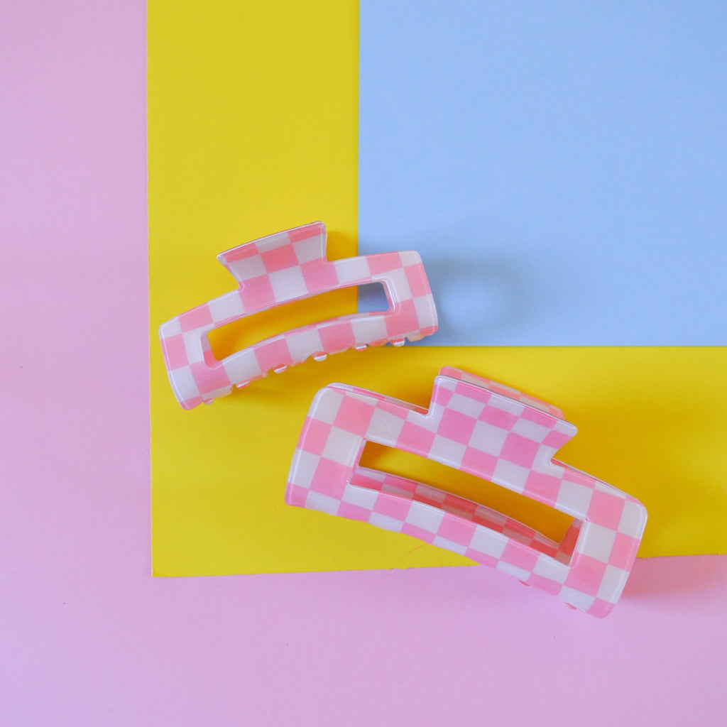 Two pink checkered hair clips on a colorful background