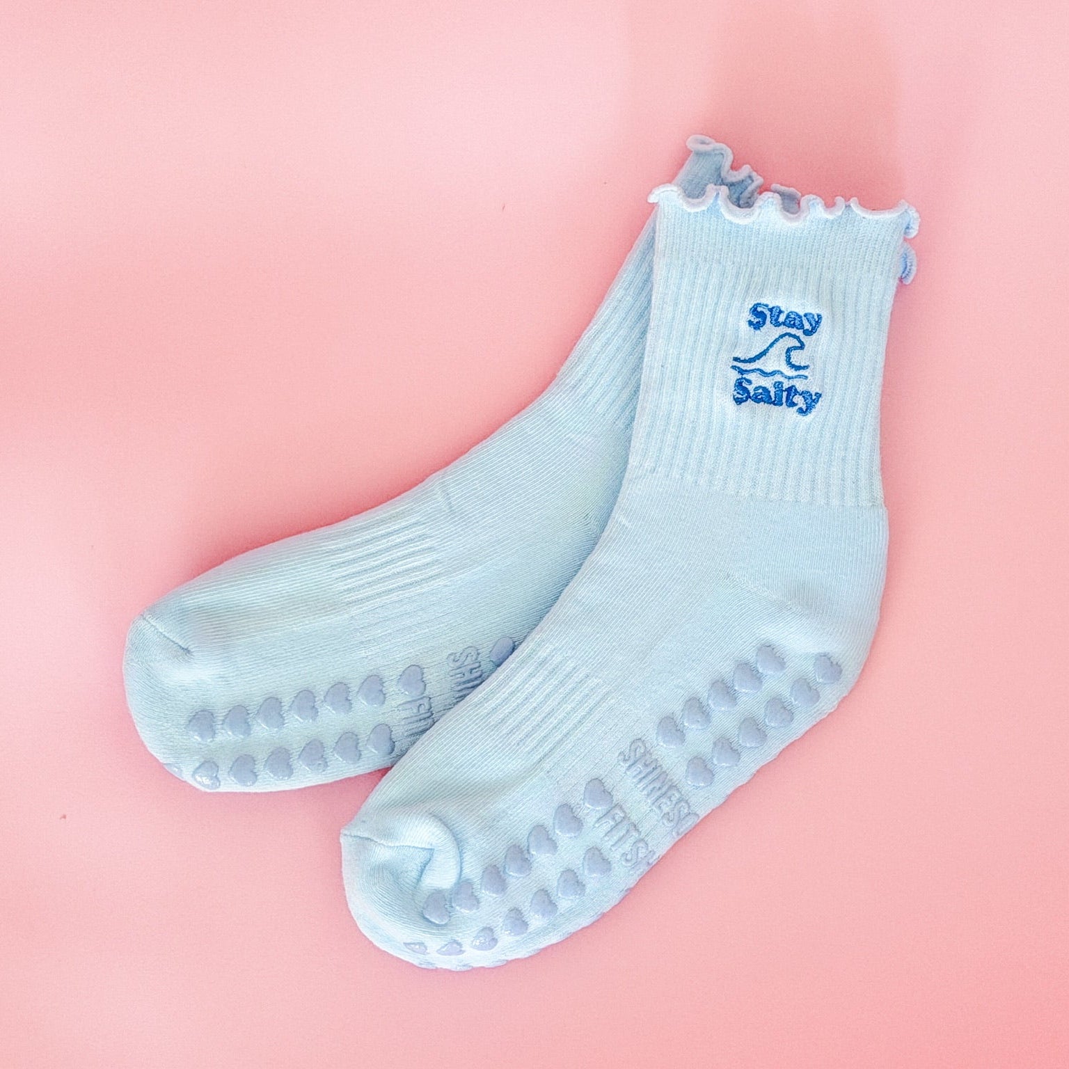 Light blue socks with Stay Salty text on a pink background