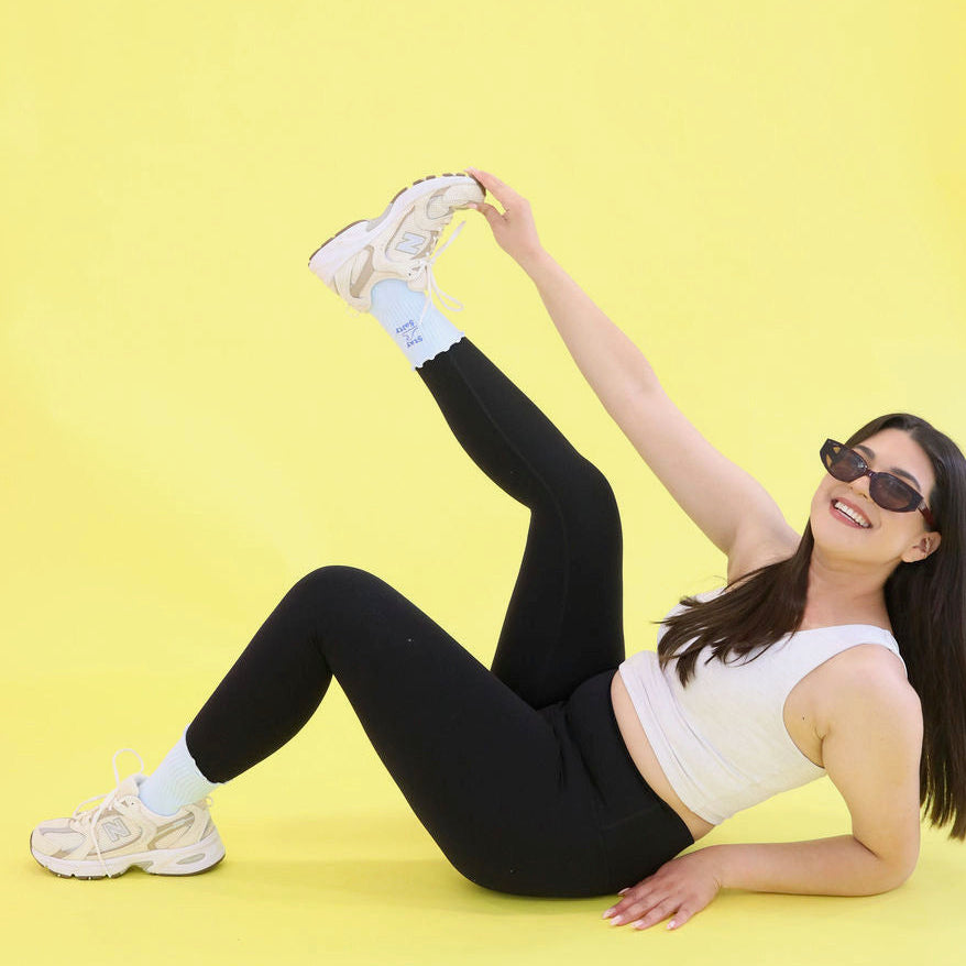 Woman stretching on a yellow with blue grip socks background