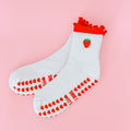 White socks with red accents and strawberry design on a pink background