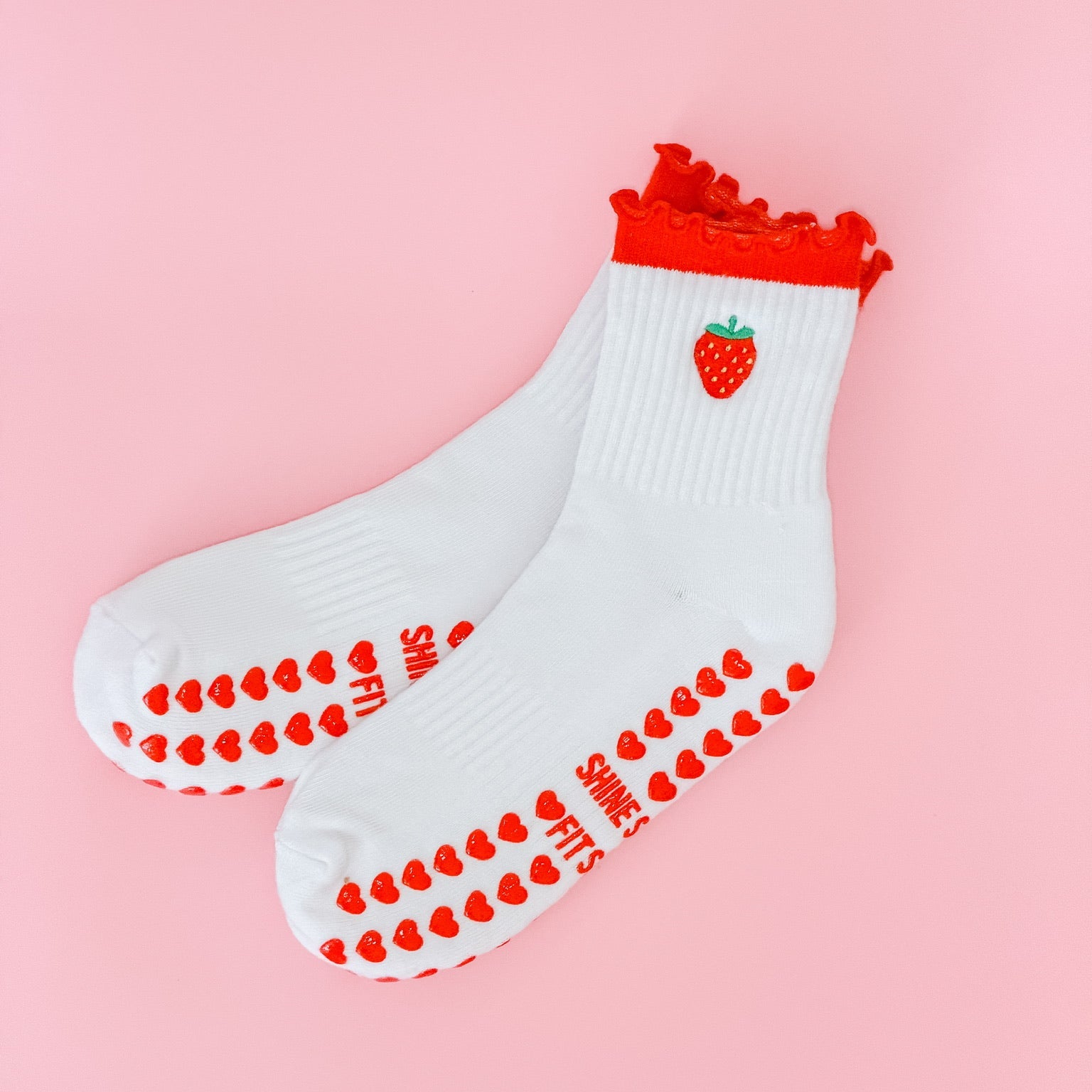 White socks with red accents and strawberry design on a pink background