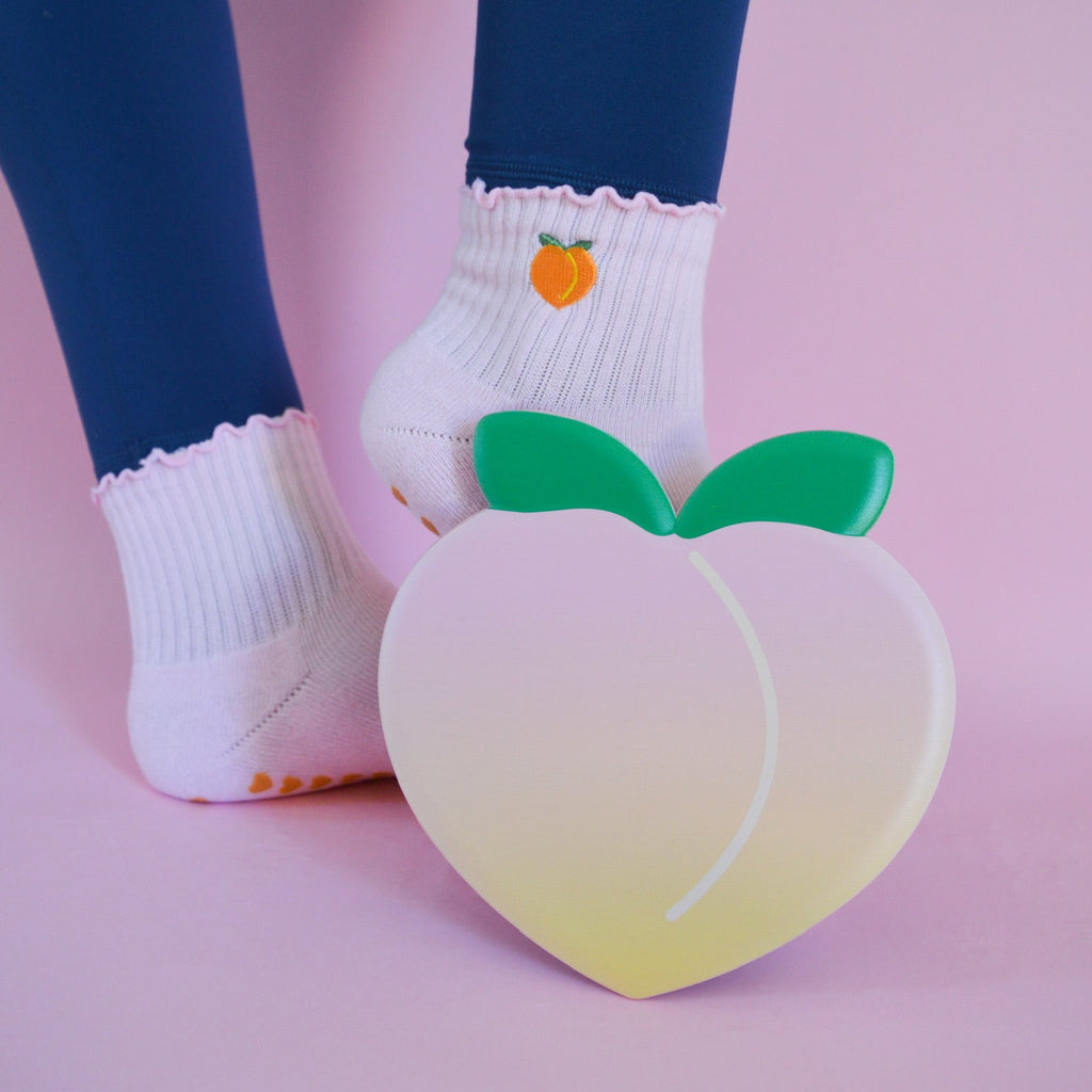 Pink socks with peach design next to a peach-shaped slider on a pink background