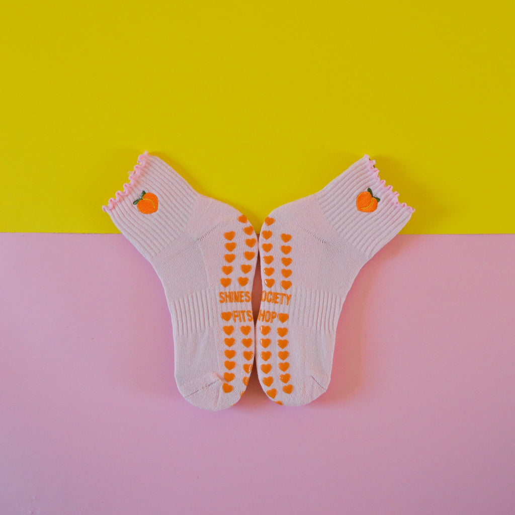 Light pink grip sock with peach on a pink and yellow background