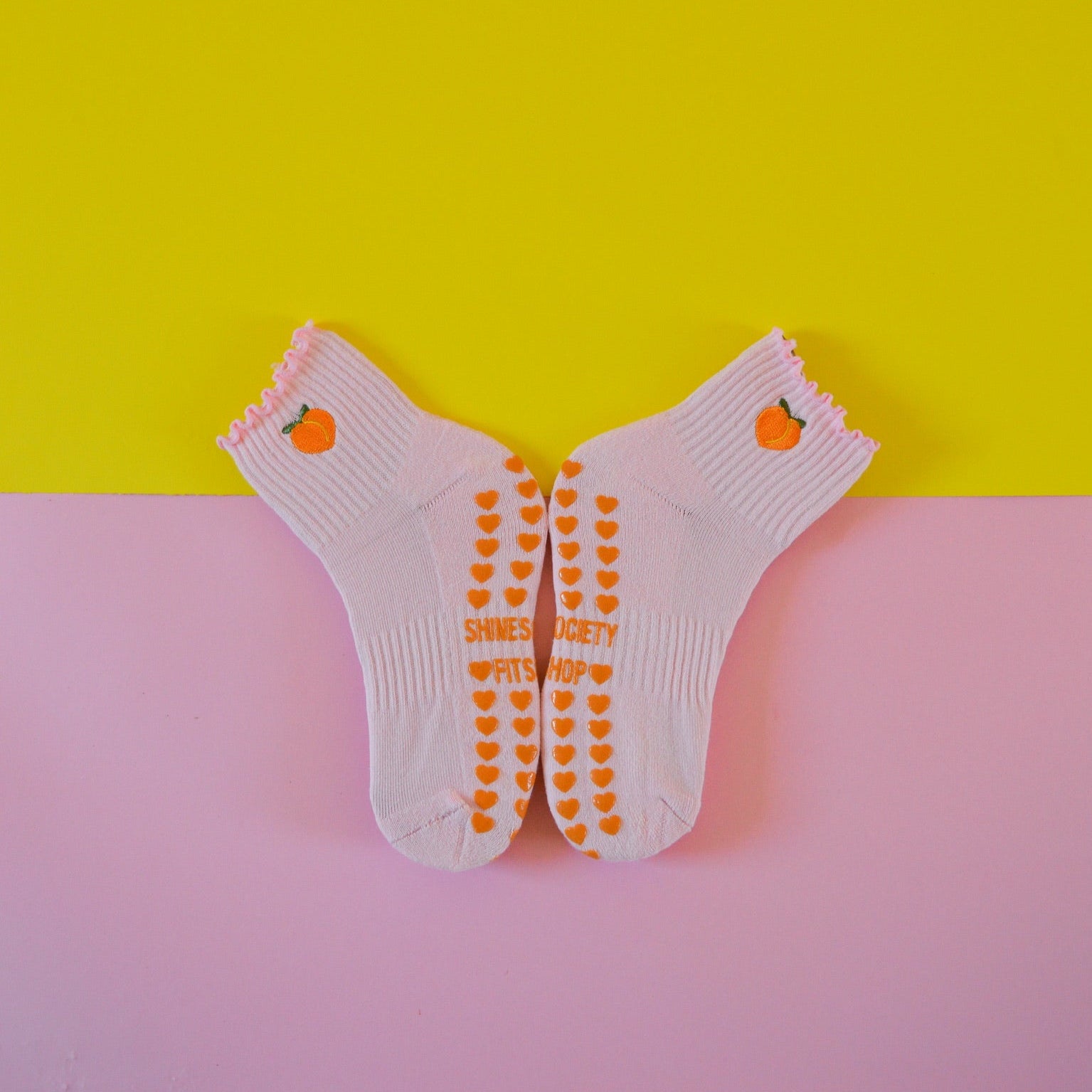 Light pink grip sock with peach on a pink and yellow background