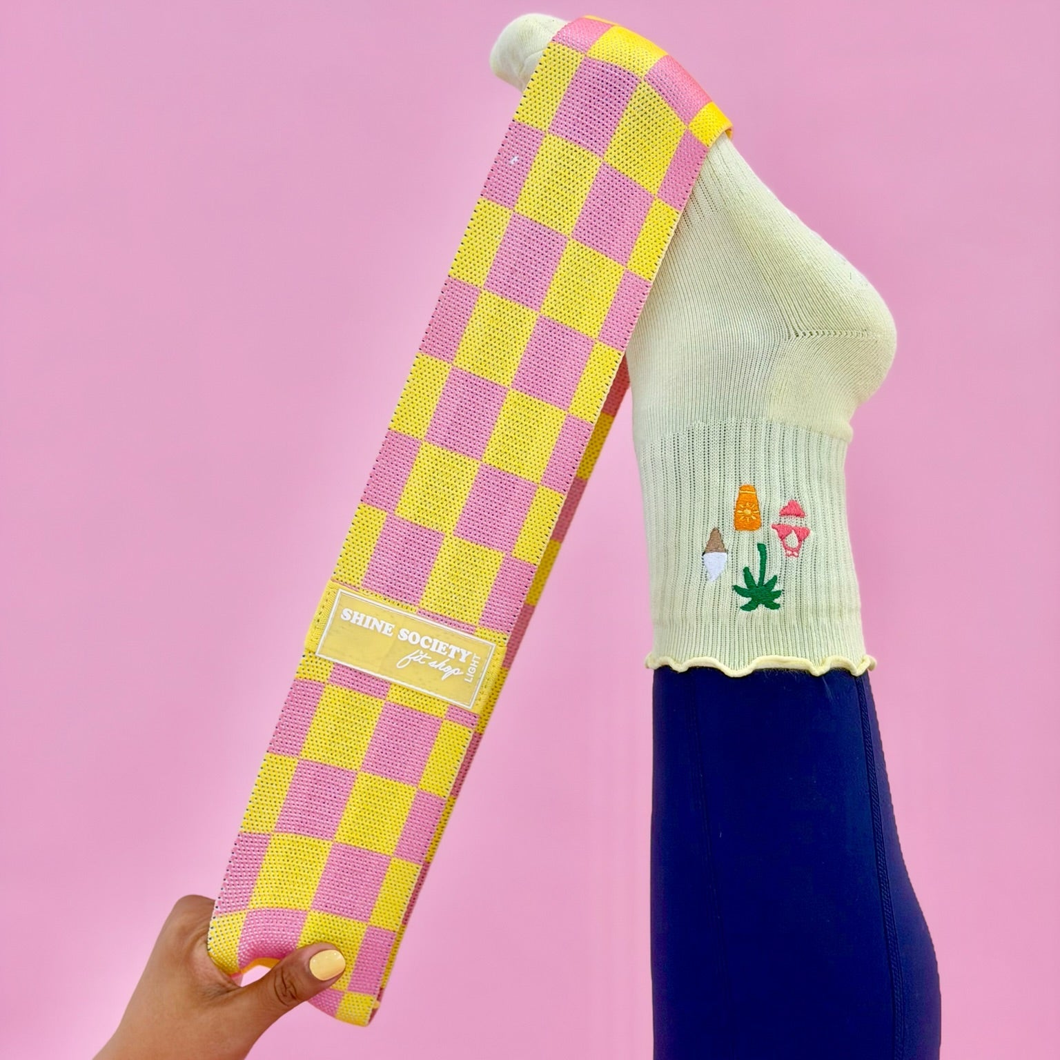 yellow sock with embroidered design held against a pink background