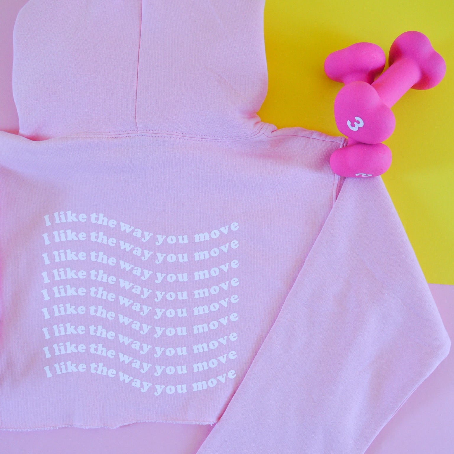 Pink hoodie with I like the way you move text and pink dumbbell on a yellow background