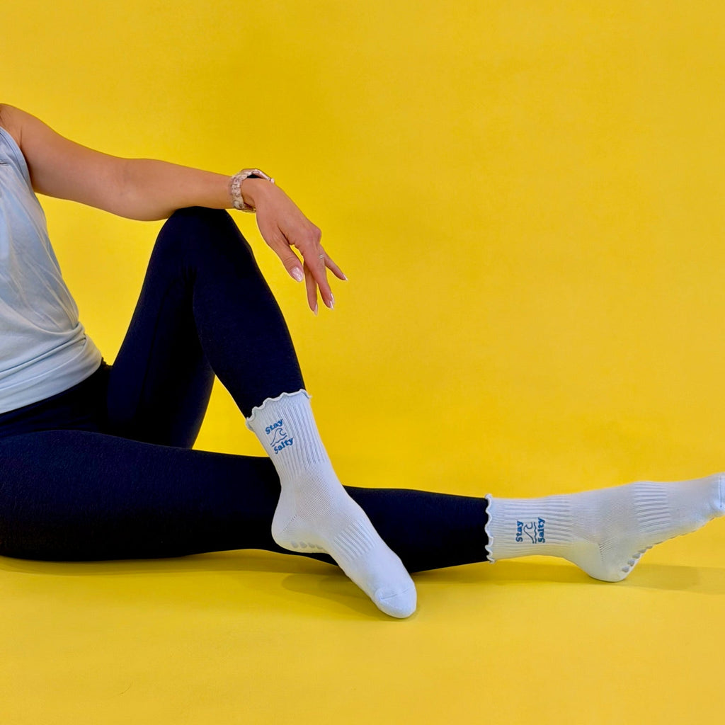 Person wearing blue socks with Stay Salty text on a yellow background