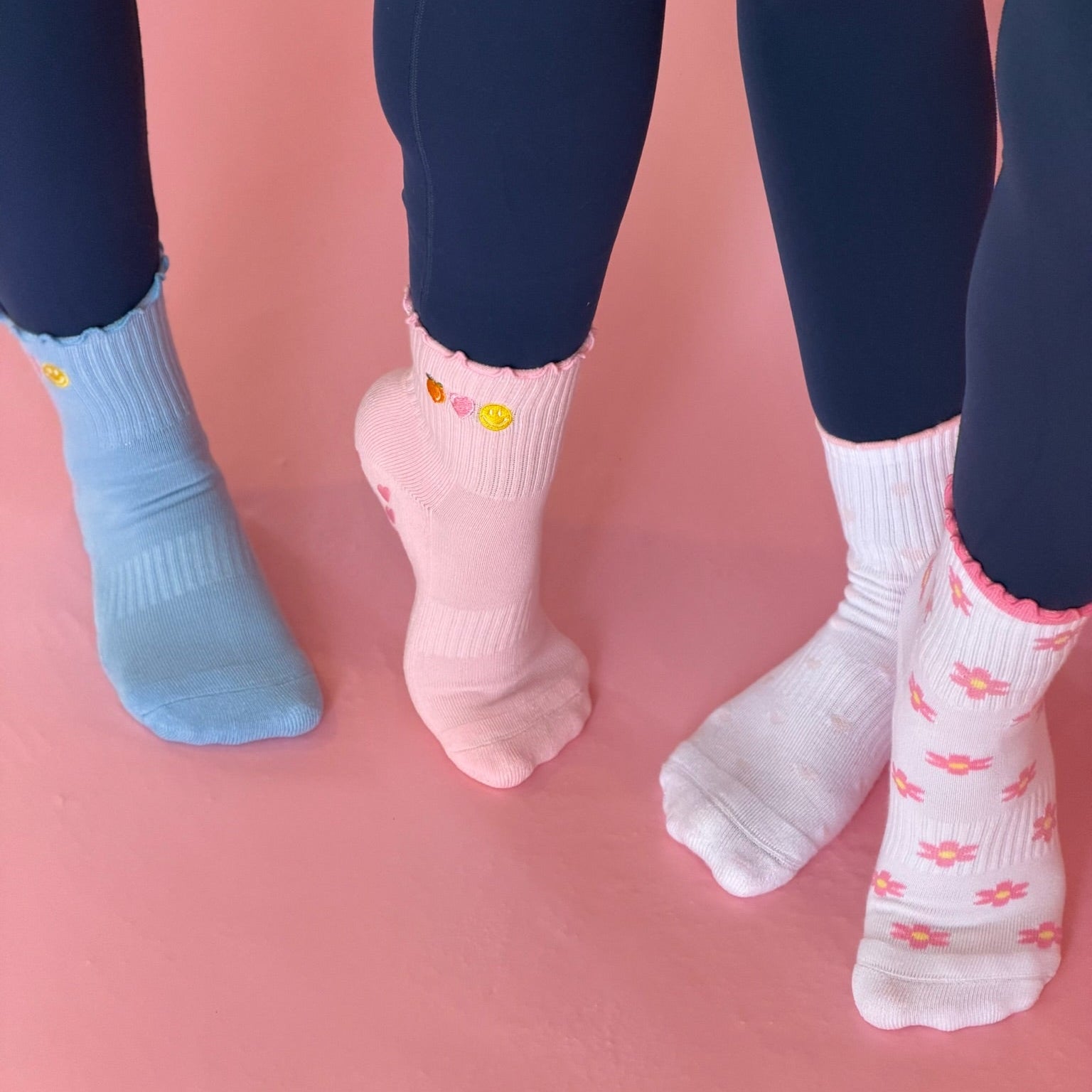 Four pairs of socks in blue, pink, and pink on a pink background