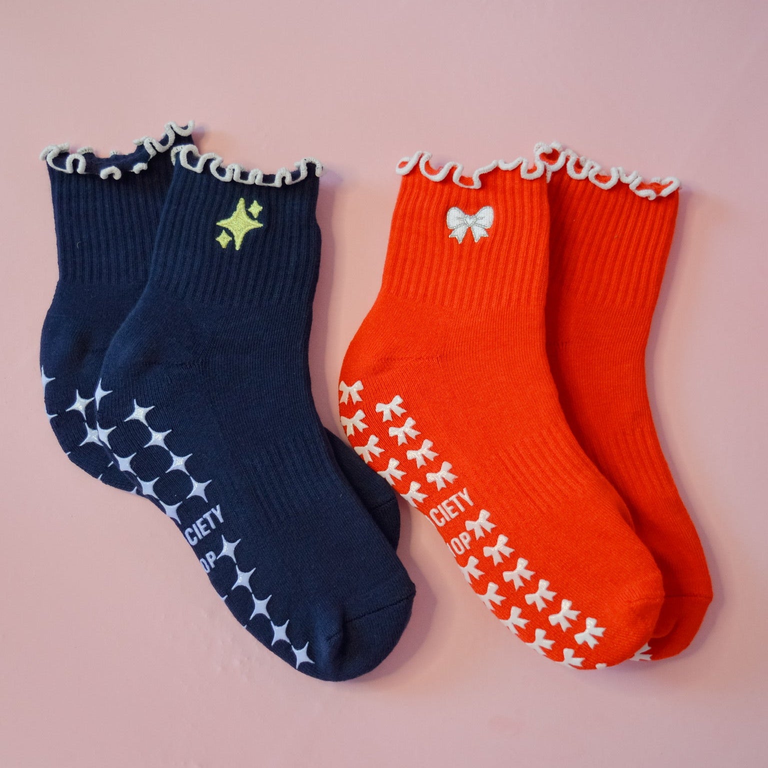 a red grip sock with white and silver bow and a navy grip sock with yellow sparkle