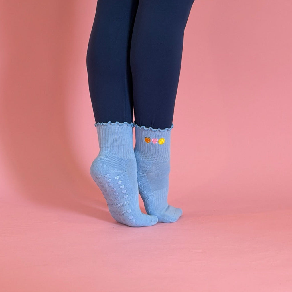 blue grip sock with peach heart and happy face on pink background