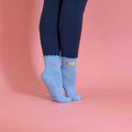 blue grip sock with peach heart and happy face on pink background