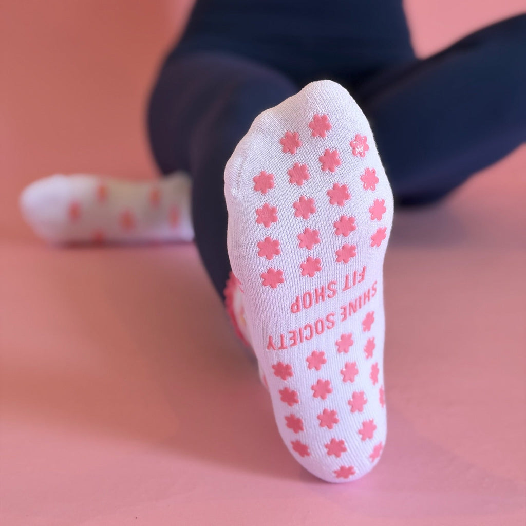 Close-up of a white sock with pink floral patterns and text on a blurred background